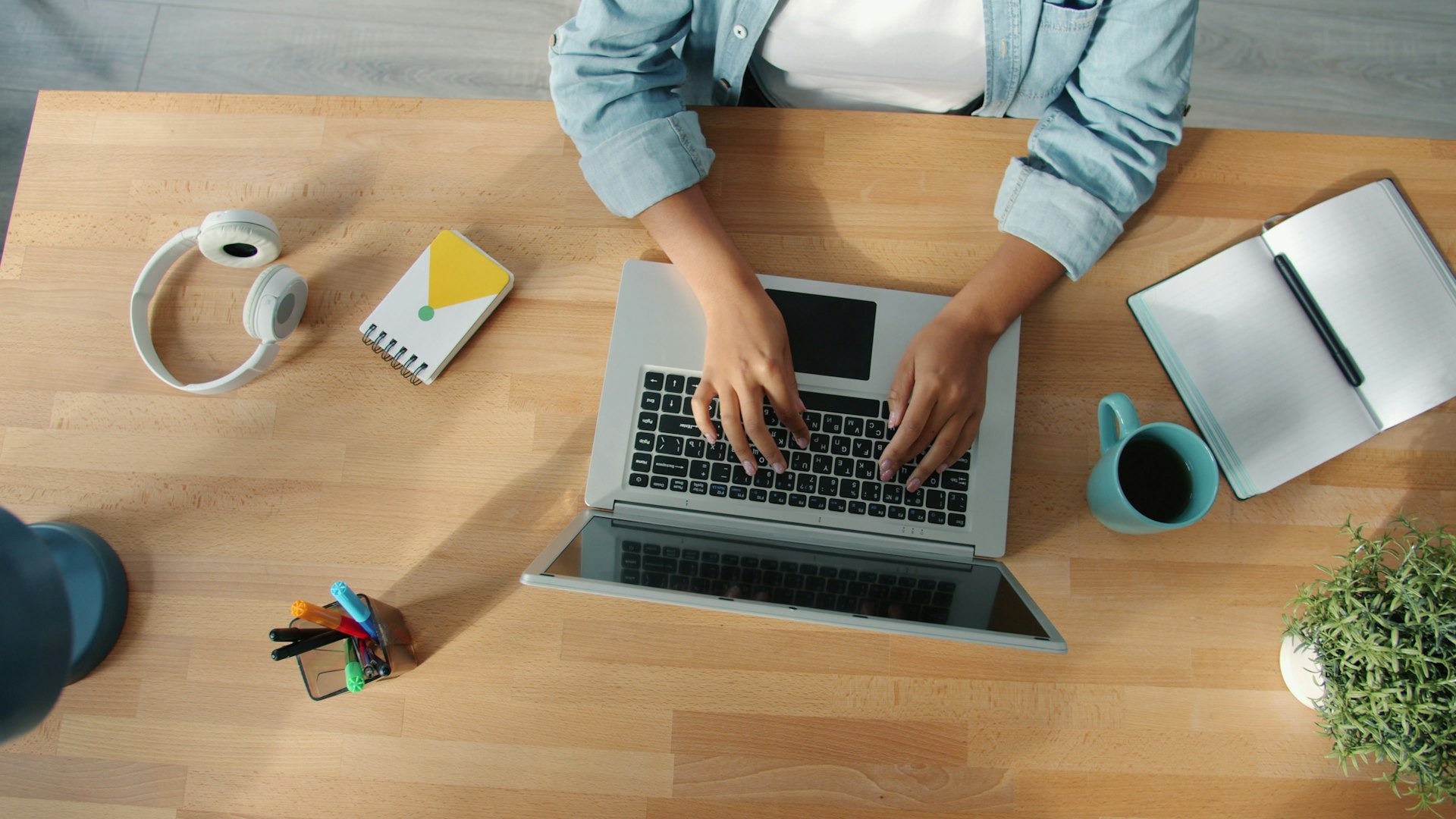 Person typing on a laptop at a wooden desk.